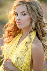 Closeup portrait of 25-30 years old woman dressed in yellow dress outdoors.