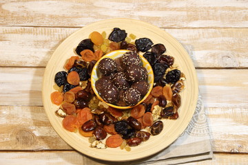 Energy balls dessert in  bowl made of dried fruits, cocoa, sesam seeds on wooden background