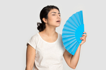 Tired exhausted Indian girl waving fan, suffering from heat