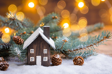 Miniature Christmas wooden house on the snow over blurred snowflakes background, toned