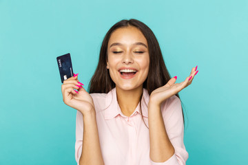 Glad and happy female person holding credit card standing on the blue background