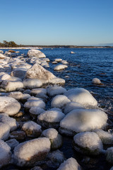 Frozen sea with snowy shores in Finland. Winter waves hitting the coast on a freezing cold sunny day. Ice and snow create unique shapes in the nature. Close-up macro photos with vibrant colors.