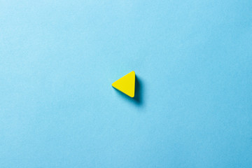 Yellow triangle on a blue background. Play sign. Minimalism. Flat lay, top view