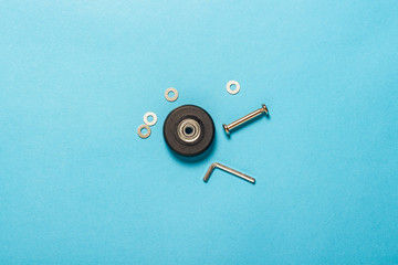 Set for repairing a suitcase or hand truck on a blue background. Wheel, nozzle, washers and tool. Repair concept. Flat lay, top view