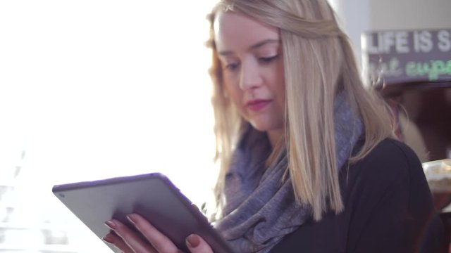 Young woman Inside Looking Down and Swiping Fingers Across iPad Tablet