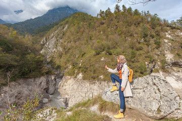 Woman takes a selfie in a mountain setting of the Dolomiti Bellunesi National Park, Italy. Concept: photography, tourism, photos of people in a natural context, travel photos