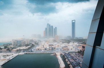 Fototapeta na wymiar Abu Dhabi during sandstorm and strong wings. View of the UAE capital downtown buildings under strong winds