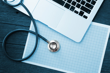 Doctor workspace with stethoscope and graph paper with computer laptop PC