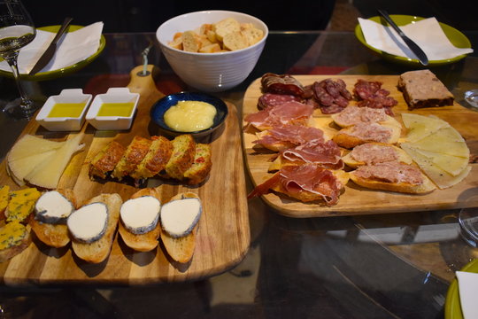 Cold cheese and meat platter including sausage,prosciutto,pate,olive oil,croutons,goat cheese on glass table in wine cellar.Wine tasting in Europe.Organic Catalan produce served in south France.Thuir