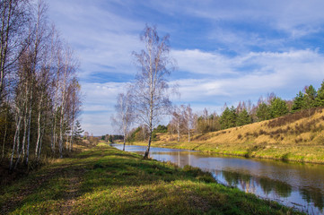 A forest river flows through a field and hills.