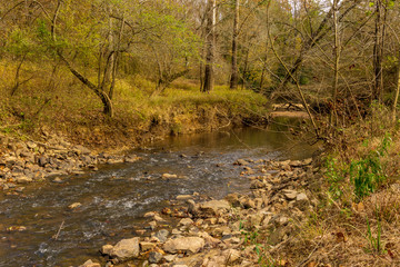 Obraz na płótnie Canvas Creek flows over rocks as it empties into larger river.