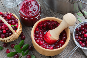 Wooden bowl and jar of crushed cranberries, jam or sauce, basket of bog berries and strainer of...
