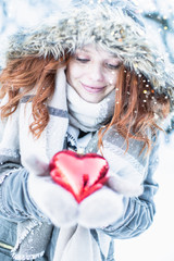 woman in winter clothes with heart in hands