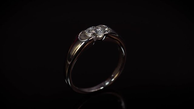 Macro view of wedding ring with diamond on black background. Luxury jewelry