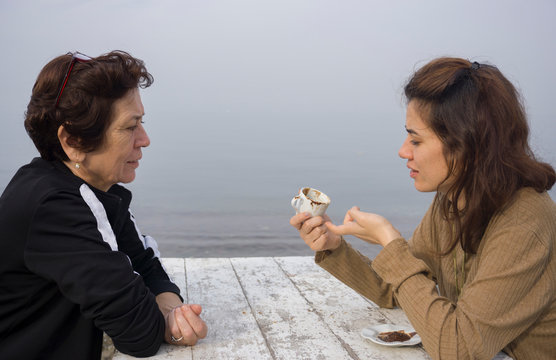 Fortune telling and traditional turkish coffee concept on coast. Woman telling fortune to elder woman by inspecting the brown grounds remaining in coffee cup. Young woman guessing on coffee grounds.