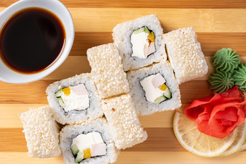 Sushi, rolls in white sesame, with cheese, avocado and shrimp. On the plank. On a red background.