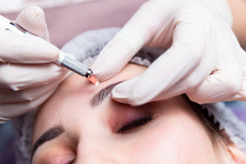 Cosmetic procedures for the treatment of eyebrows. Microblading in the beauty salon. Professional cosmetology. The process of applying the pigment.