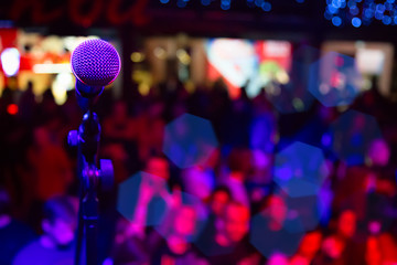 Close up of microphone in concert hall or conference room. Microphone on stage with colorful...