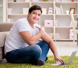 The man working on laptop at home on carpet floor