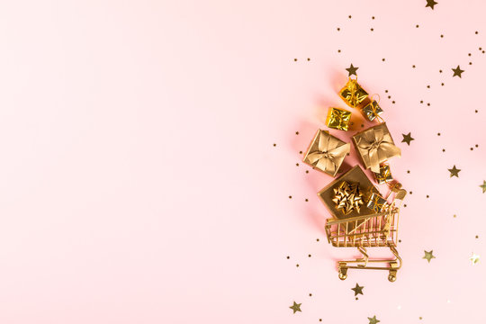 Shopping cart trolley basket gold color Christmas decor with gifts. isolated on pink background. Conception Festive Sale Discount. Trading Supermarket Retail.Flat lay.Copy space .
