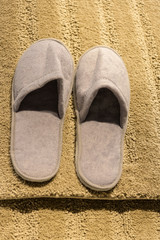 Beige slippers on a yellow carpet close-up.