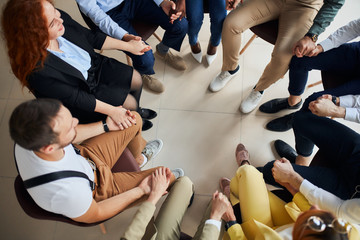 Young leaders, co-workers, business team hold hands together while sitting on chairs in circle, wearing formal wear. creative business people concept