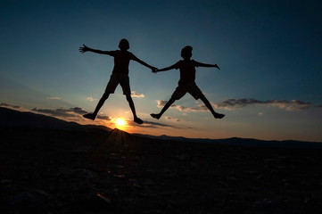 jumping boys silhouettes at sunset