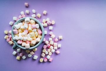 Hot chocolate with colorful marshmallows on purple background. Top view. Copy space.