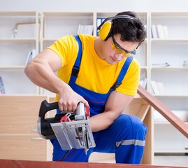 Repairman carpenter cutting sawing a wooden plank with a circula