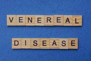 Fototapeta premium phrase venereal disease made from brown wooden letters lies on a blue table