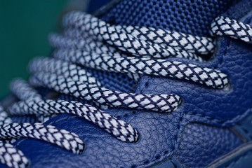white lace on the blue leather of the shoe with a seam