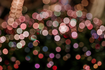 Illuminated abstract round pink, yellow purple and gold bokeh on dark background. Colourful glitter bokeh from out of focus view of decoration bulbs.