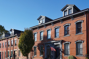 Old brick row houses with dormer windows and American flag