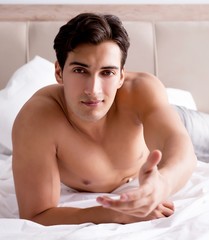 Young handsome shirtless guy showing nude torso sexy on bed at h