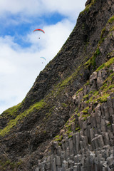Naklejka premium Two paragliders flying above a mountain with basalt columns in southern Iceland
