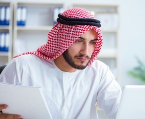 Arab businessman working in the office doing paperwork with a pi