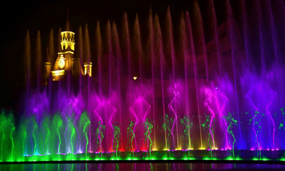 Naklejka na ściany i meble Colorful water fountains. Beautiful laser and fountain show. Large multi colored decorative dancing water jet led light fountain show at night. Dark background.