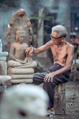 Ayutthaya/Thailand-March 9, 2017: An old Thai man is cleaning a stone-carved Buddha image. To worship,Ayutthaya,Thailand.
