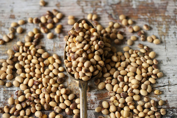 Soybeans in a spoon and sprinkled on a wooden surface. Organic soybeans.