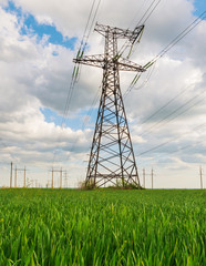 Electrical net of poles on a panorama of blue sky and green meadow