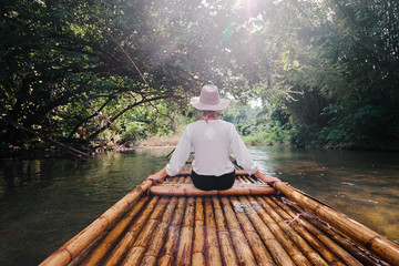 Traveling by Thailand. Back view of tourist enjoying view sailing jungle river on traditional...
