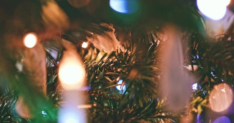 Festive White Ornaments and Twinkling Lights on a Christmas Tree. SLOW MOTION CLOSE UP. Happy preparation for winter holidays, bulbs, toys and candles on a fir tree. Cozy atmosphere.