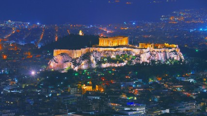 Cityscape of Athens with illuminated Acropolis hill, Pathenon and Herodium construction and sea at...