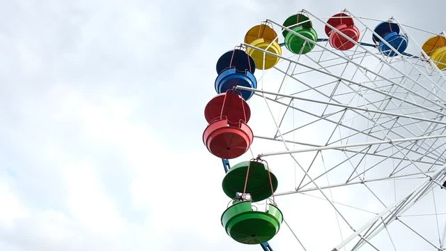 Recreation park, attractions for children and adults. Ferris wheel. Carousel. Colorful, multi-colored seats against a blue sky. Summer. Day.