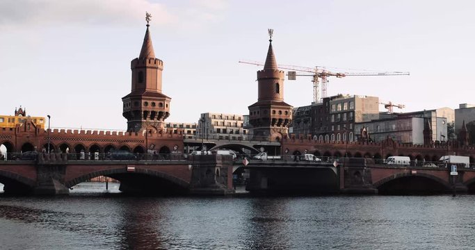 A Yellow S-bahn travels across the Oberbaum Bridge during sunset as the camera jibs up.