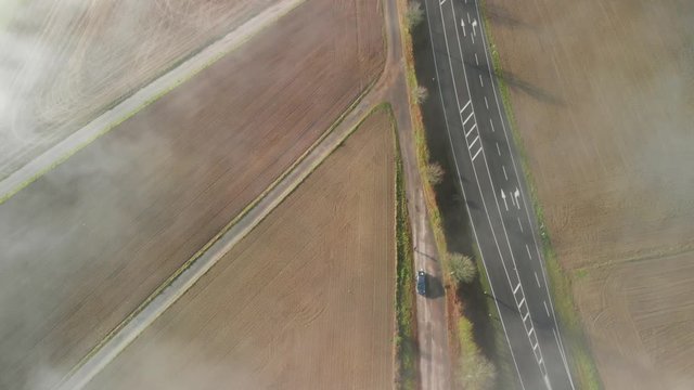 A road through a rural agricultural area in Luxembourg, top down shot of a morning with fog.