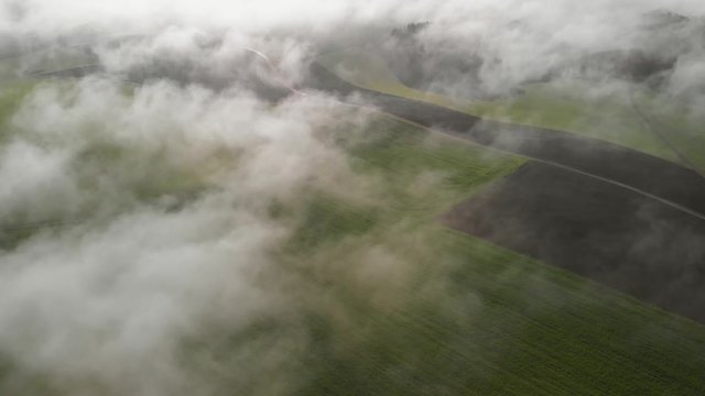 Aerial shots above the morning fog with a view of a couple of windturbines. Revealing aerial shot in Luxembourg.