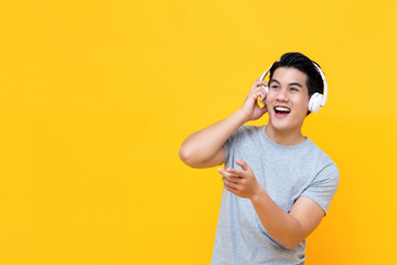 Handsome happy Asian man listening to music on headphones and smiling