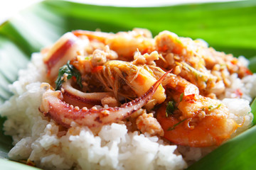 stir fried basil with seafood or shrimp and squid with chili on white rice and green banana leaf dish for nature lunch and traditional spicy Thai food in restaurant or street food