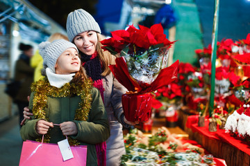 Young girl and her mother are buying Christmas ornamentals in the market outdoor.
